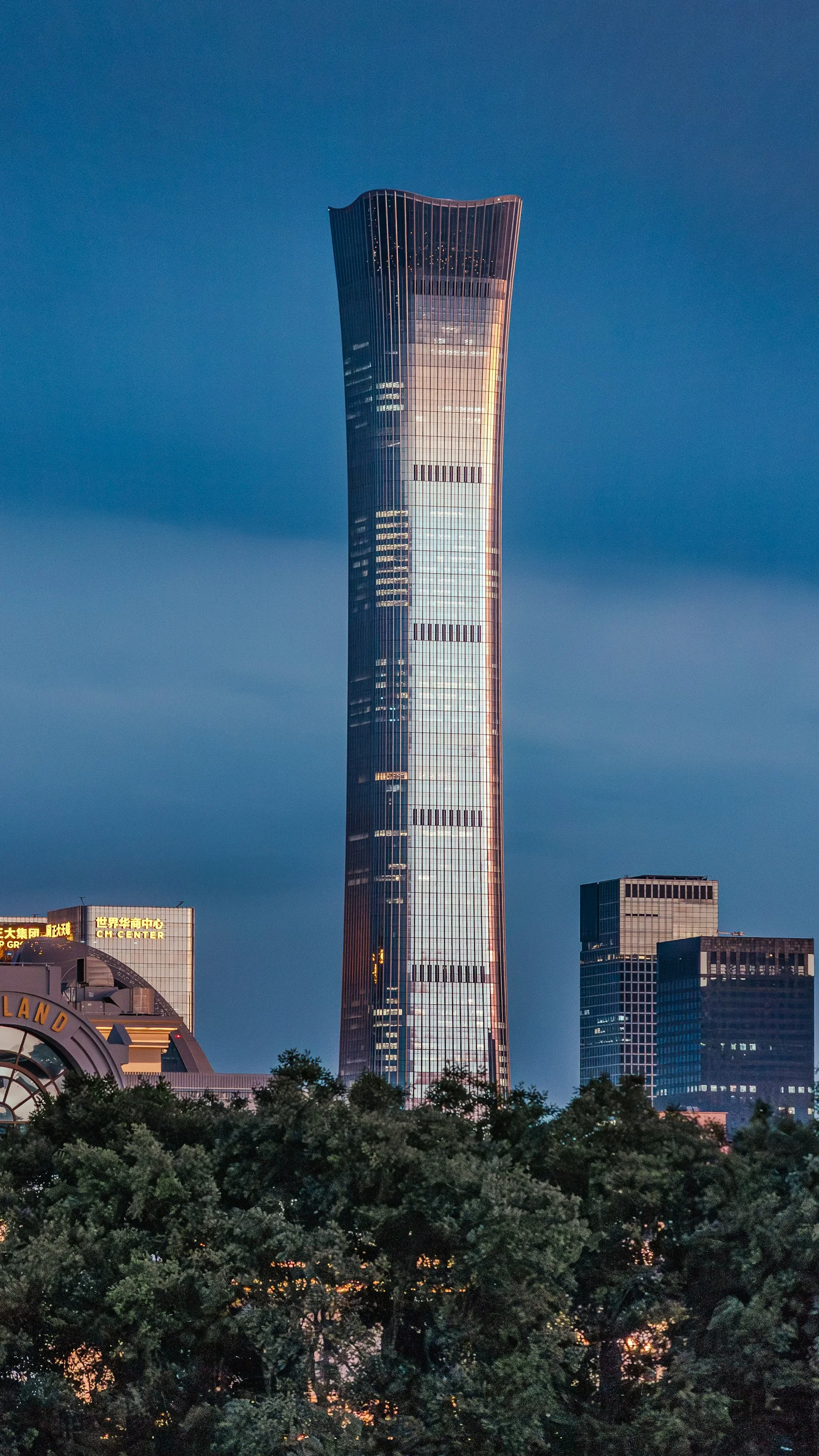 Beijing's contemporary central business district rises above active roads and a public crossing at blue hour.
