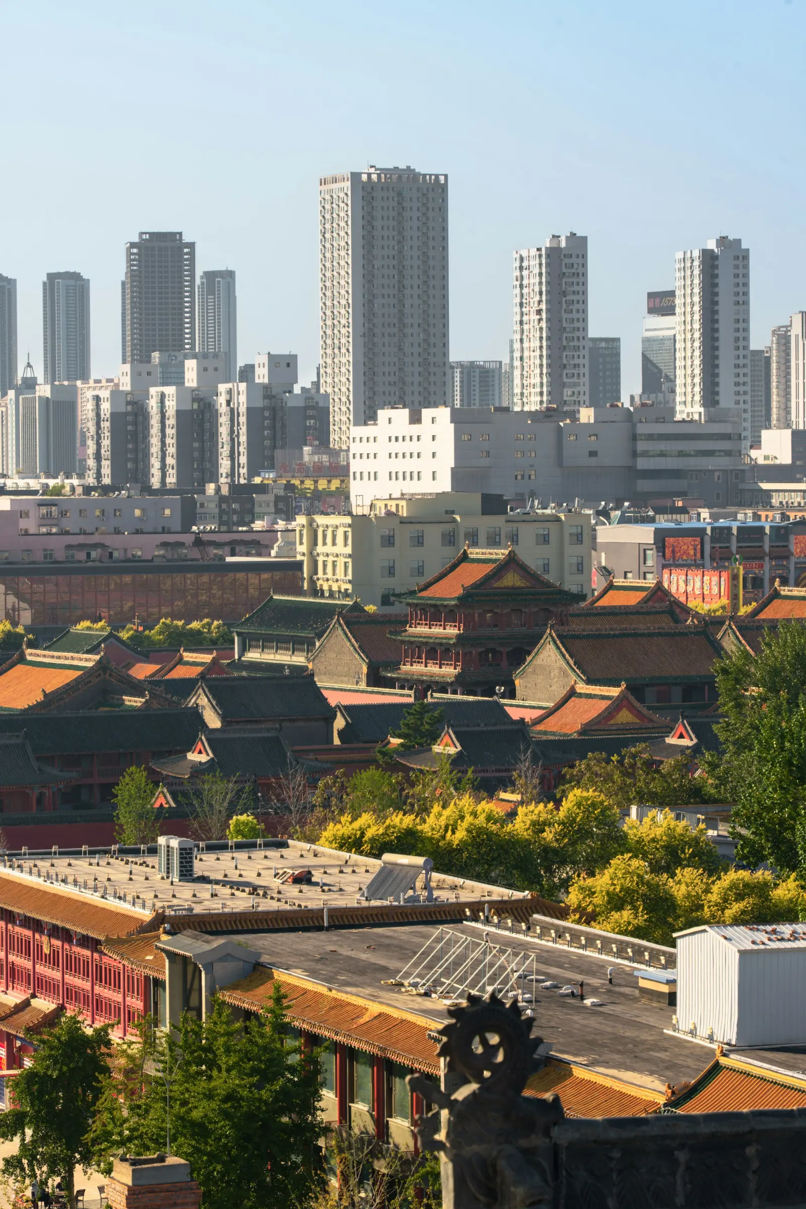 The tiled roofs of the Shenyang Imperial Palace sit in the foreground with contemporary residential and office towers rising behind them.