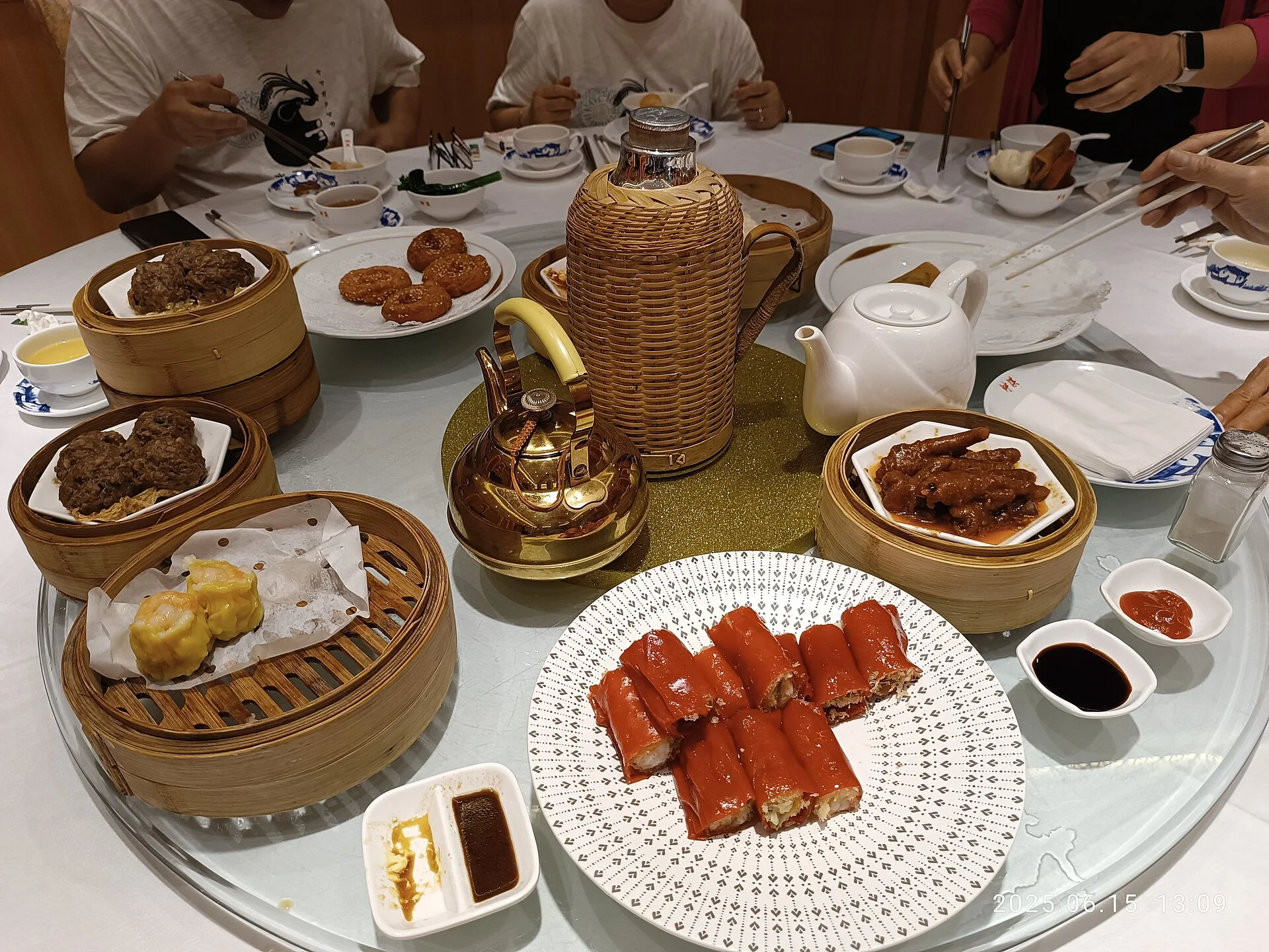 A Guangzhou yum cha table crowded with bamboo steamers and small dishes for sharing.