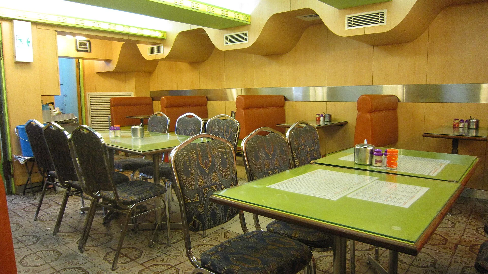 A compact Hong Kong cha chaan teng interior with close-set booths, tiled floor and practical table settings.