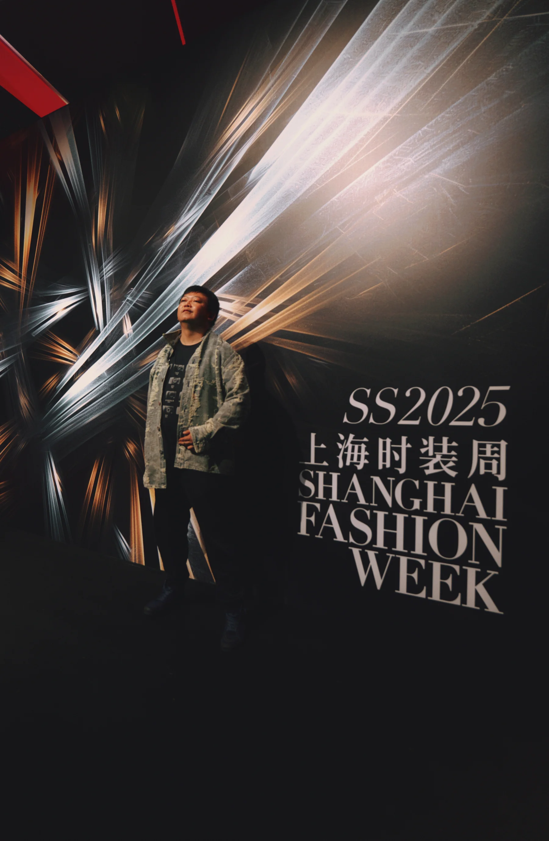 A photographer works beside a Shanghai Fashion Week runway as models and audience occupy the surrounding space.