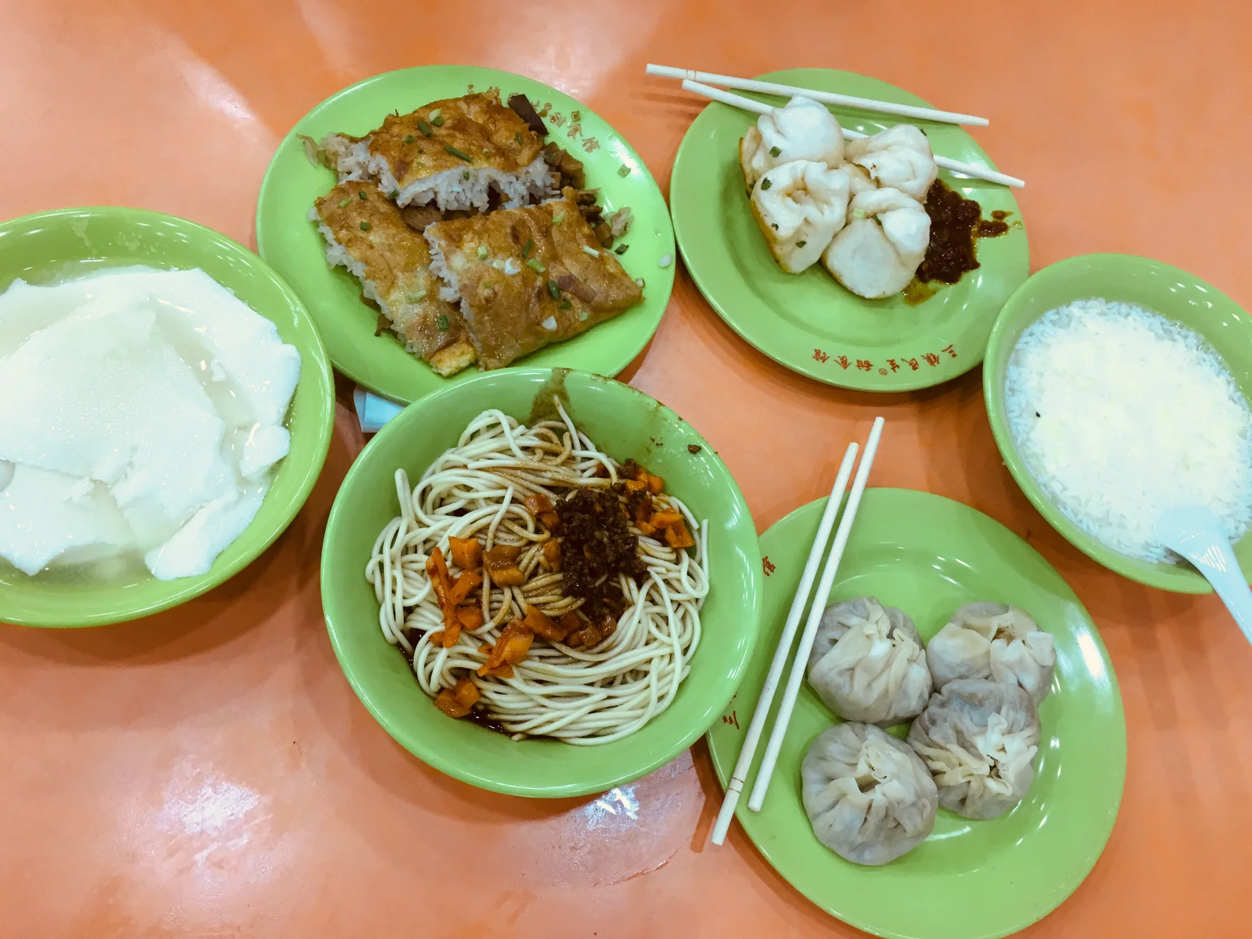 A Wuhan breakfast table with hot dry noodles, doupi, buns, tofu pudding and a rice-wine drink.