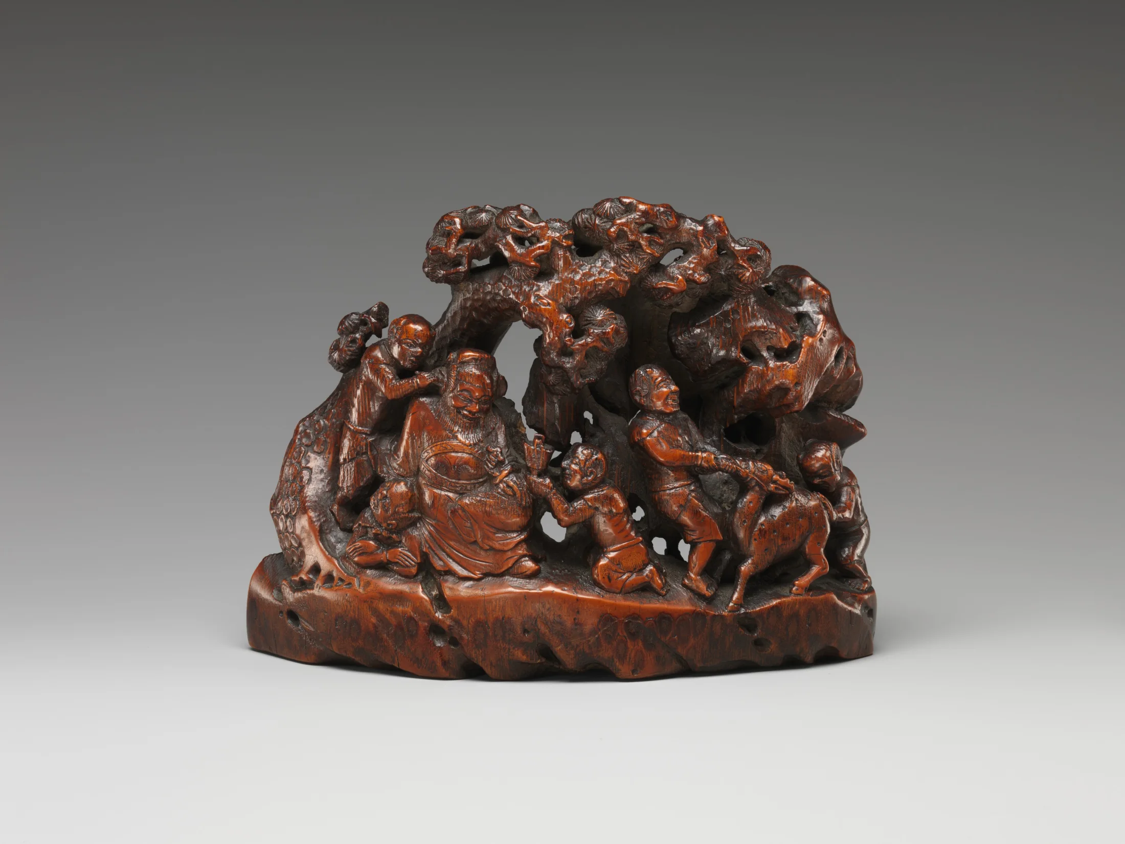 A Qing-dynasty bamboo carving shows the seated demon-queller Zhong Kui surrounded by smaller demon attendants.