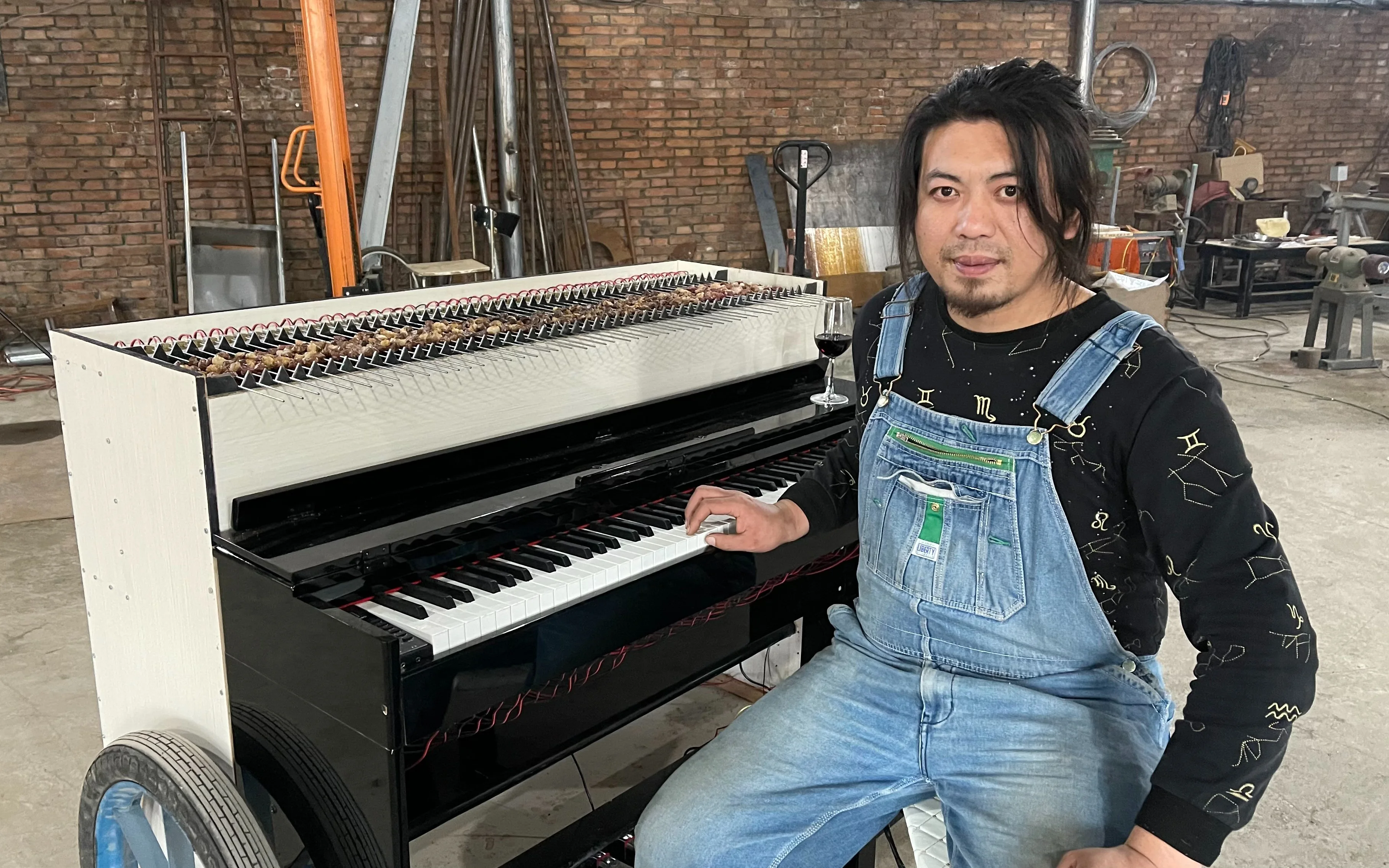 Hand Geng sits at a metal barbecue cart fitted with piano keys in his original Bilibili video.
