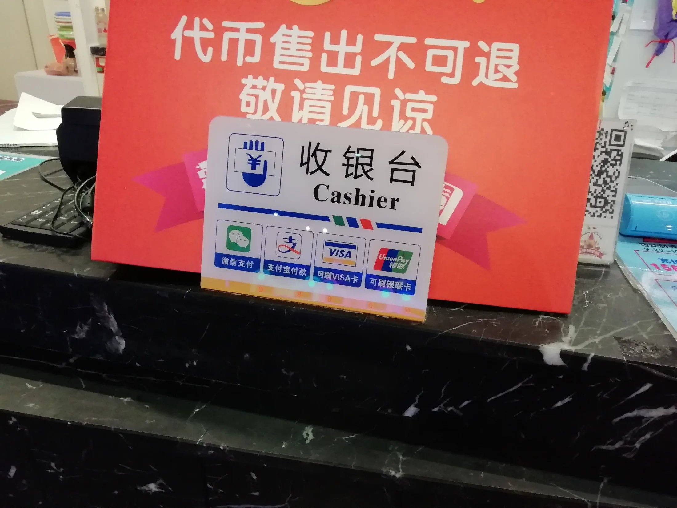 A cashier sign in a Suzhou shop lists Weixin Pay, Alipay, Visa and UnionPay beside a service QR code.