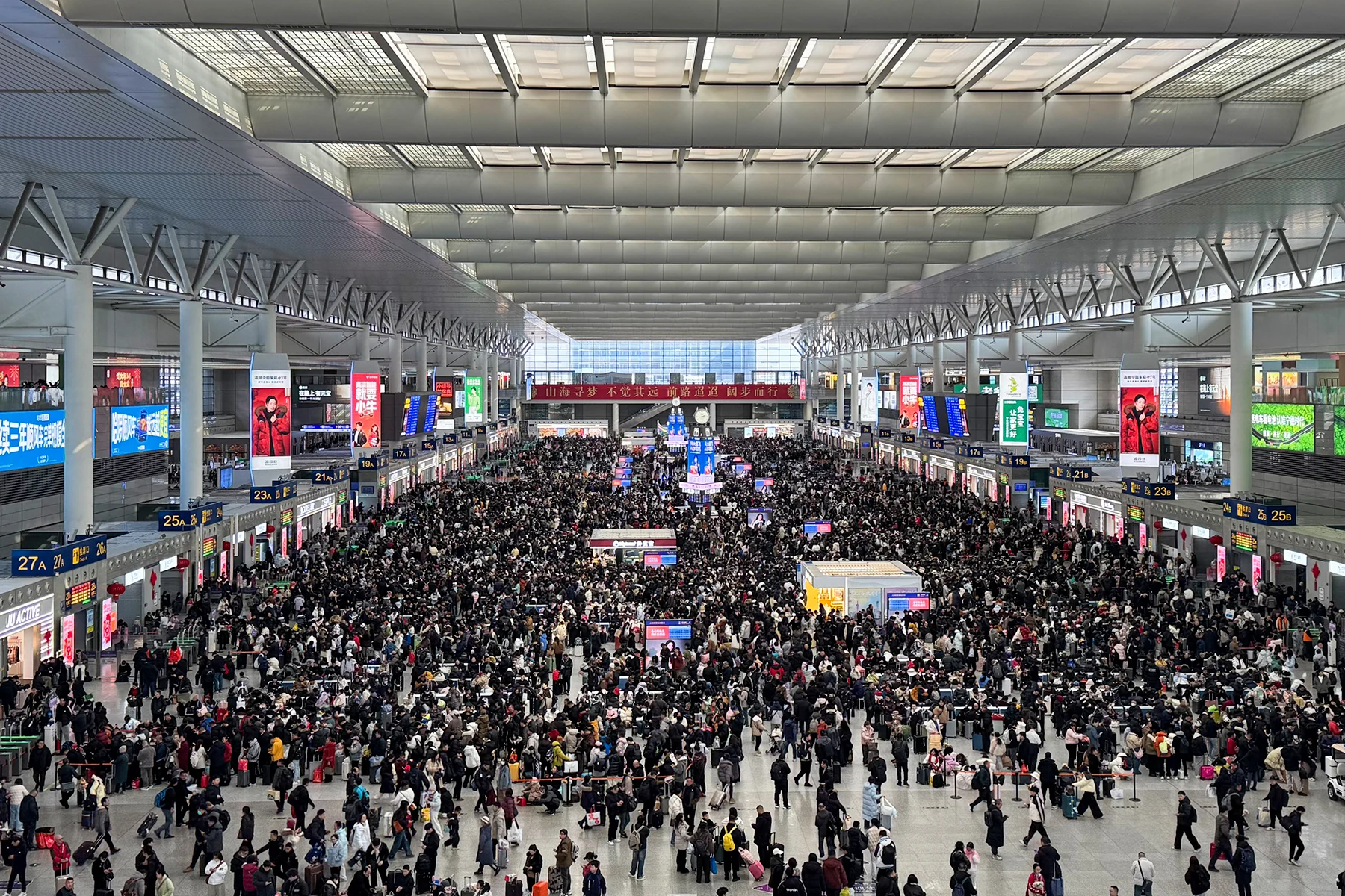 Travelers carrying luggage fill the bright Shanghai Hongqiao Railway Station concourse during the 2026 Spring Festival travel rush.