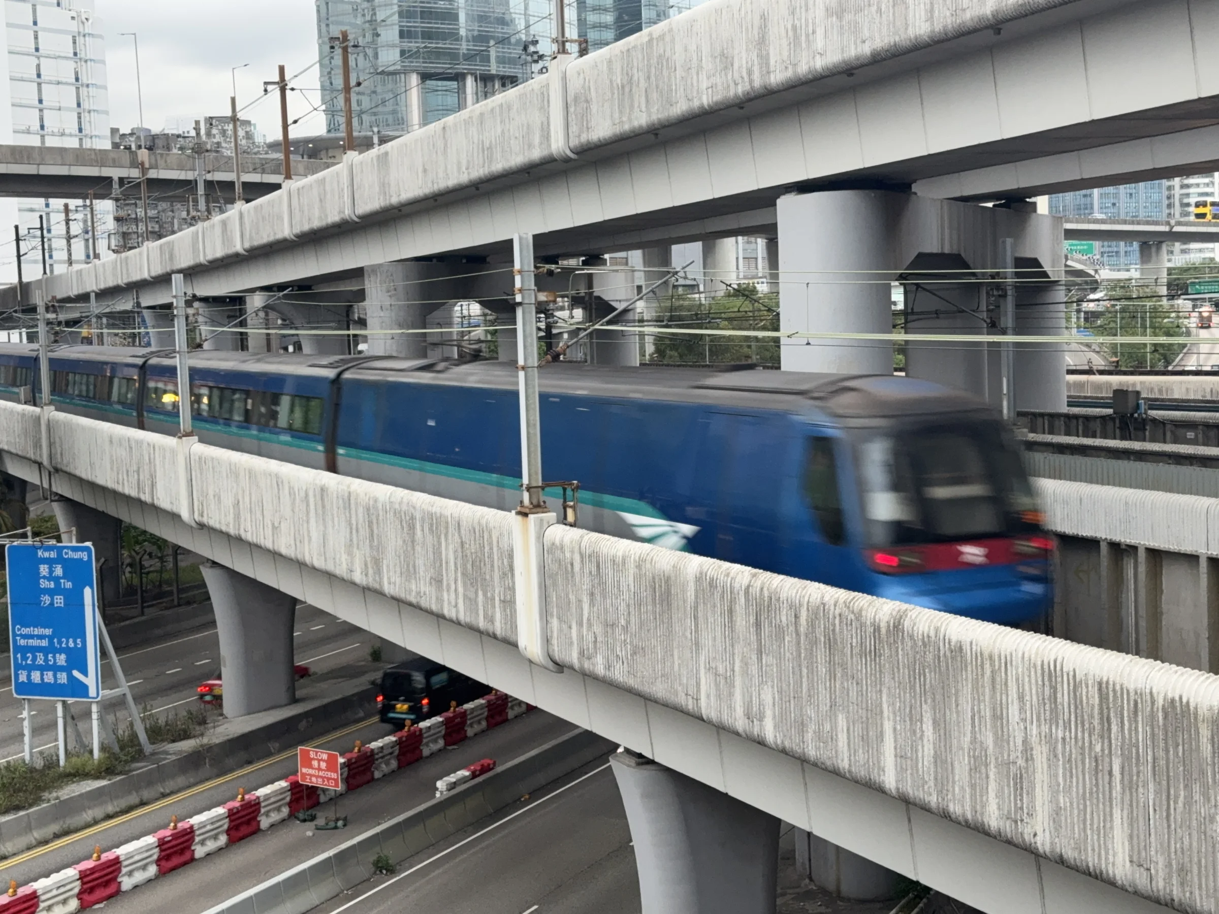 A Hong Kong Airport Express train moves through a layered elevated rail and road junction near Lai King.