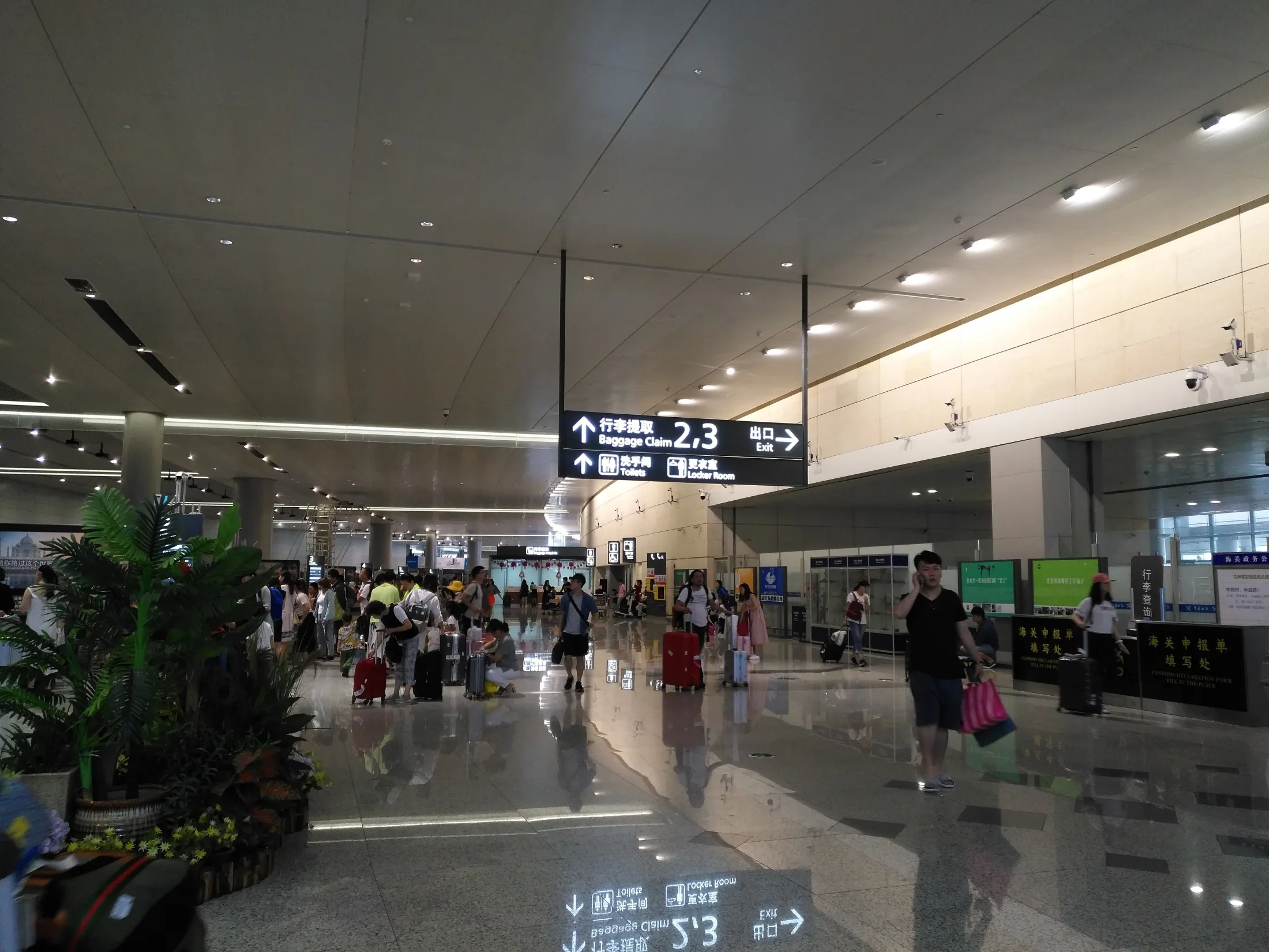 Travelers with luggage move through the international arrivals area at Nanjing Lukou Airport Terminal 2.