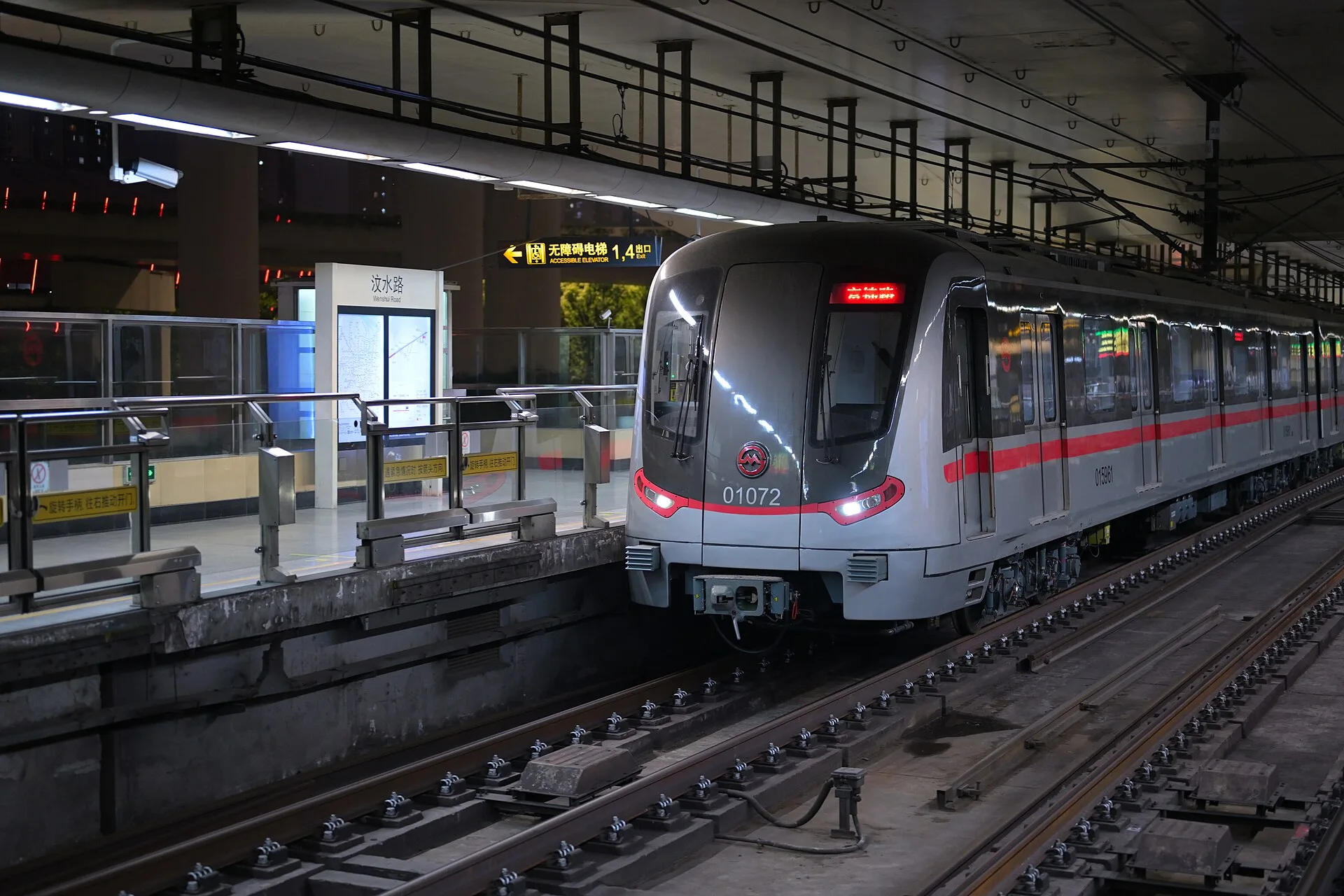 A Shanghai Metro Line 1 train stopped at Wenshui Road station, with the bilingual station sign, platform screen doors and accessibility sign visible.