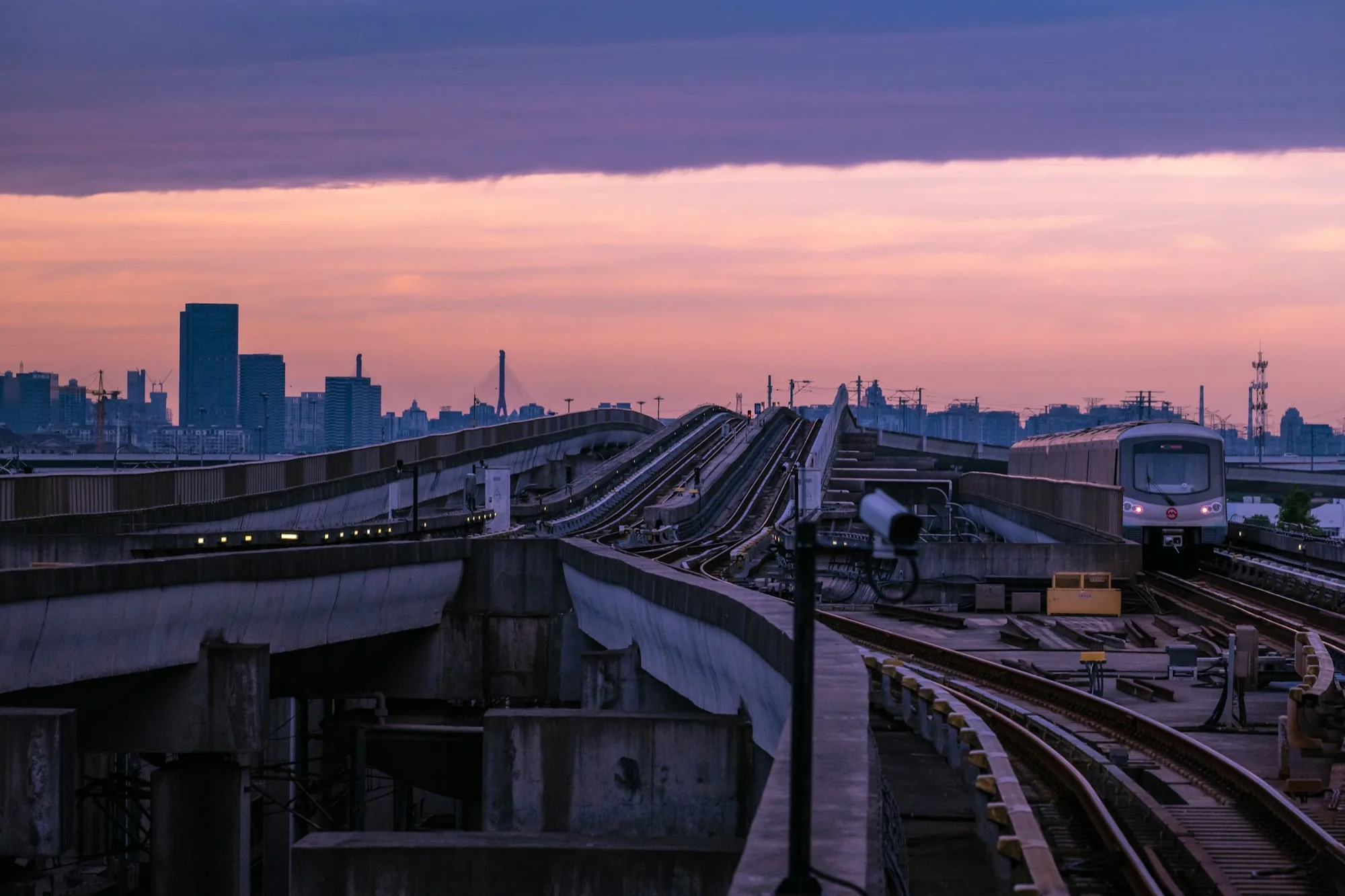 A Shanghai Line 16 metro train approaches on elevated tracks after rain at blue hour.