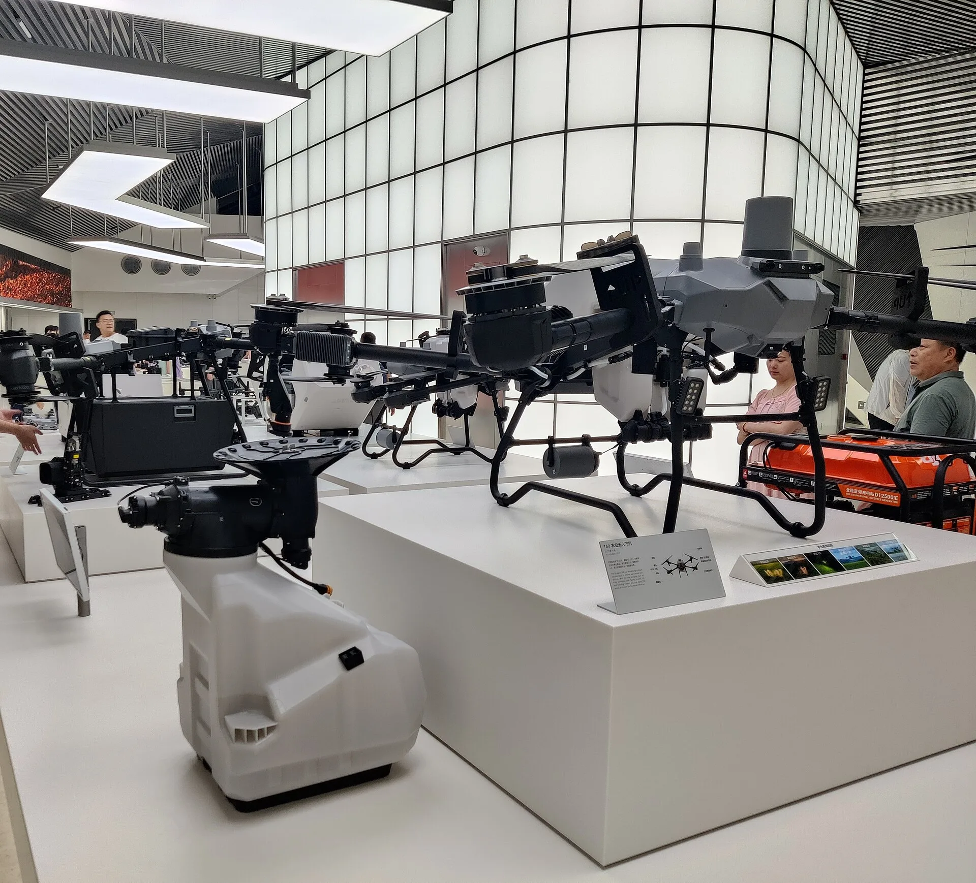 Several large DJI agriculture drones displayed in a DJI store, revealing cameras, tanks, rotors and landing structures at close range.