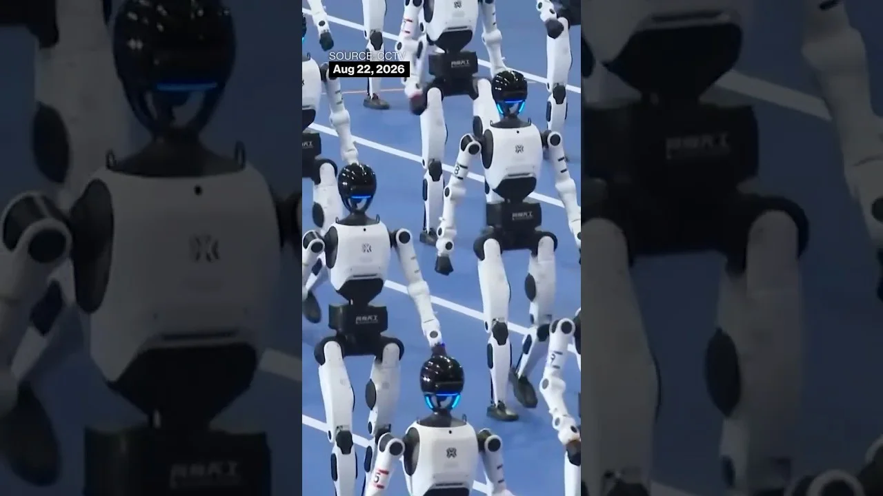 Humanoid robots move together on the blue competition floor at Beijing's 2026 World Humanoid Robot Games.